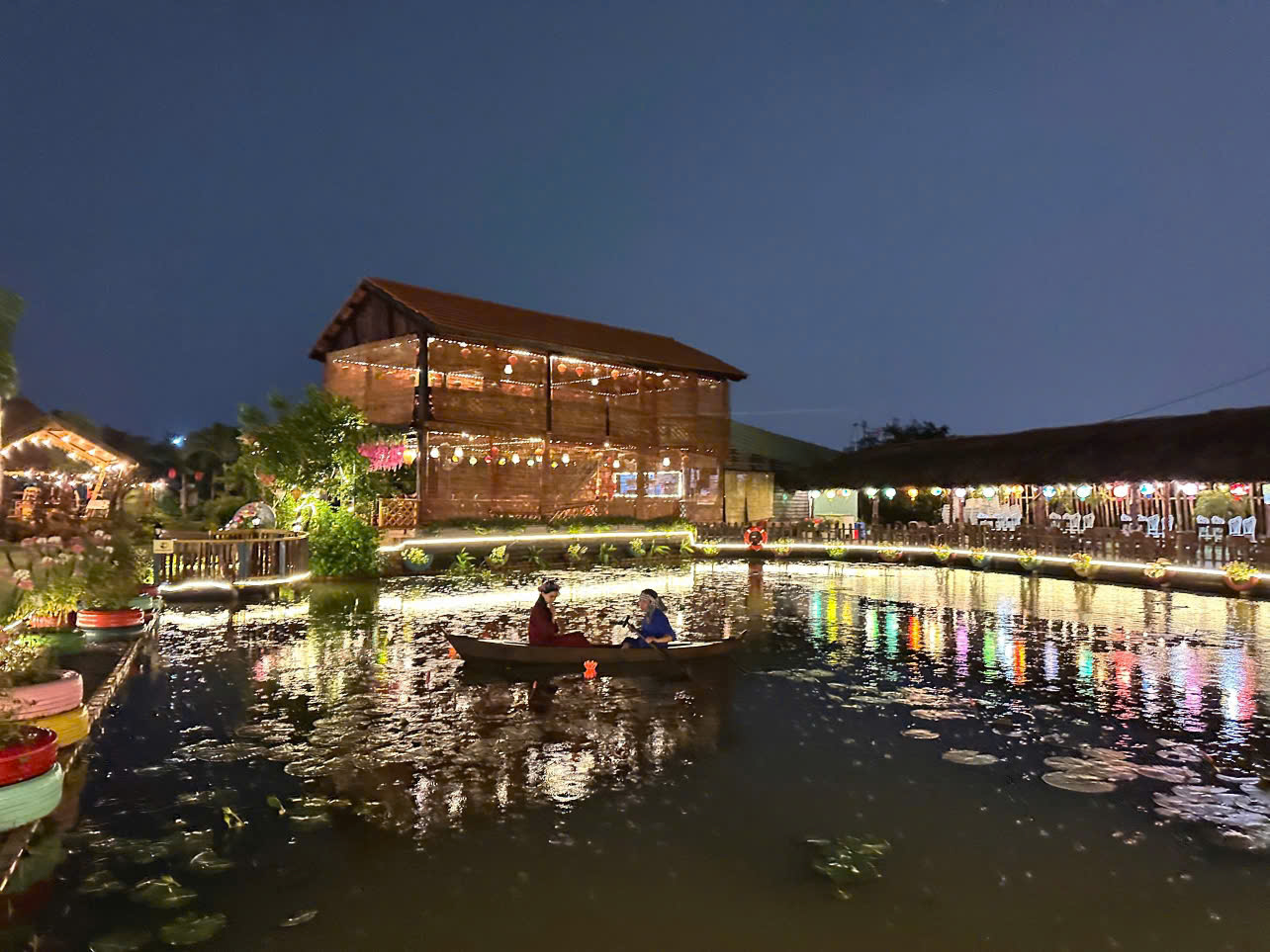Toàn Cảnh Hồ Nước và Nhà Sàn Gỗ 2 Tầng Rực Rỡ Ánh Sáng Về Đêm tại Sen Vàng Garden Hóc Môn